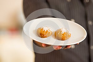 Man is holding a delicious turkish dessert sekerpare with coconut powder