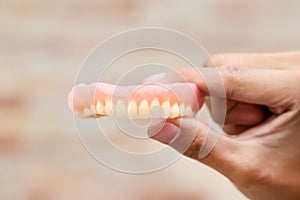 A man is holding dentures in his hands. Removable dentures flexible. False teeth