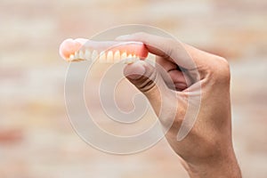 A man is holding dentures in his hands. Removable dentures flexible. False teeth