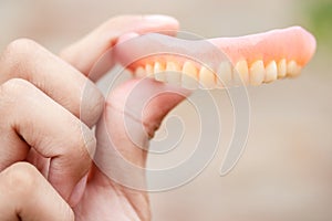 A man is holding dentures in his hands. Removable dentures flexible. False teeth