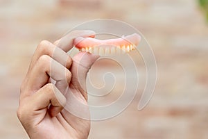 A man is holding dentures in his hands. Removable dentures flexible. False teeth