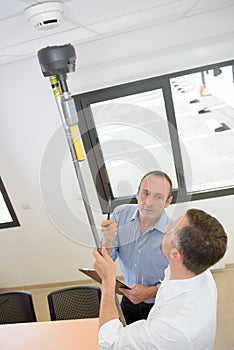 Man holding device for testing smoke alarms