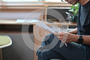 Man holding digital tablet and reading document on sofa.