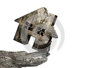 Man holding dirty concrete house on cliff edge