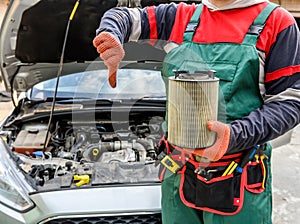 Man holding dirty filter near car at workshop