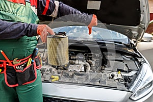 Man holding dirty filter near car at workshop