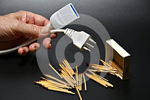 A man is holding disconnected electric power cords with matches. electricity supply problem concept. blackout