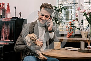 Man holding a dog while making a phone call