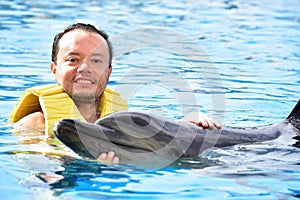 Man holding dolphin in pool