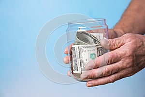 Man holding donation jar with money on color background