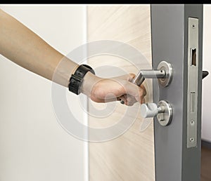 Man holding door handle of stainless steel on wooden door to open and show the door Latch