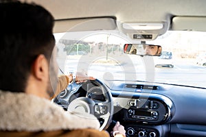 Man holding driving wheel riding car looking in rearview mirror at daytime