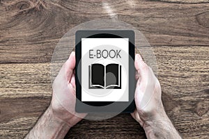 Man holding e-book reader on rustic wooden table