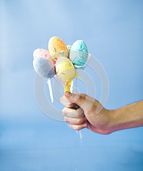 Man holding Easter eggs on a stick on a blue background