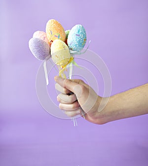Man holding easter eggs on stick on violet background