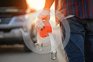 Man holding emergency car towing line and standing infront of car on the roadside. Car accident, repair and maintenance concept