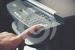 Man holding finger on start button of  printer