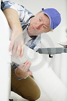 man holding flexible hose in roofspace