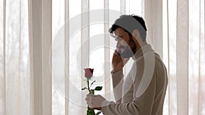Man holding flower and phone.