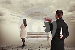 Man holding flowers and knife behind back