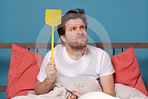 Man holding a fly swatter wanting to kill annoying mosquito
