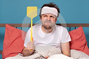 Man holding a fly swatter wanting to kill annoying mosquito