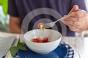 Man holding a forkful of tomato mozzarella salad