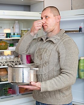 Man holding foul food near fridge