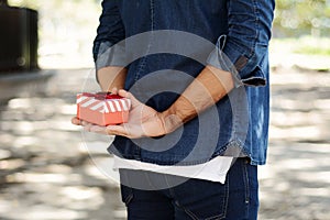 Man holding a gift box behind his back.