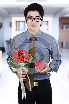 A man holding gift box and flowers