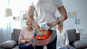 Man holding gift boxes behind back for mother and wife, women day celebration