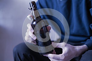 man holding the glass bottle of alcohol sitting at home in depression, bad habit problem