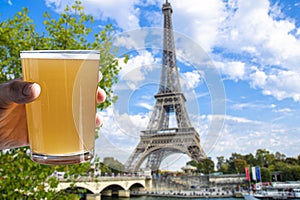 Man holding glass of light beer on Eiffel tower background