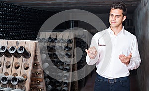 man holding glass with wine in cellar