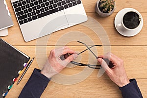 Man holding glasses while working on laptop