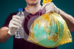 A man holding globe in plastic bag and plastic bottle. Earth pollution and environment pritection concept