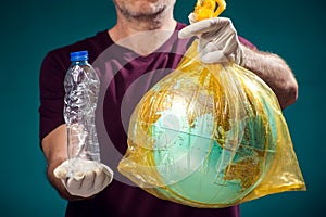 A man holding globe in plastic bag and plastic bottle. Earth pollution and environment pritection concept