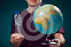 A man holding globe and plastic bottle. Earth pollution and environment pritection concept