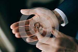 The man is holding a gold wedding ring. Wedding accessories