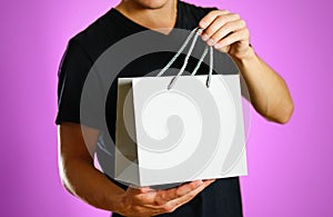 A man holding a gray gift bag. Close up. Isolated background