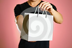 A man holding a gray gift bag. Close up. Isolated background