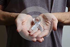 Man holding gray ribbon. Awareness ribbon