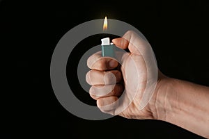 Man holding green lighter on black background, closeup