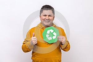 Man holding green recycling signboard pointing finger at camera, calling for garbage sorting.