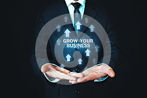 Man holding Grow Your Business words with growth arrows. photo