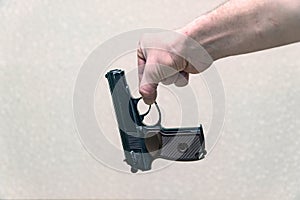 Man holding the gun with two fingers on a gray background