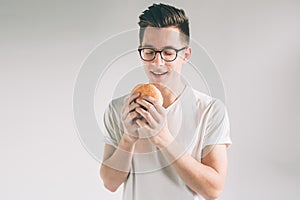 Man holding hamburger. student eats fast food. not helpful food. very hungry man. Nerd is wearing glasses.