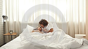 Man holding hand and looking at girlfriend on bed