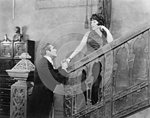 Man holding the hand of a woman standing on a staircase