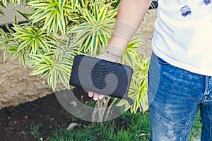 Man holding handmade purse made from exotic leather snakeskin python, outdoors, green tropical background. Bali island.